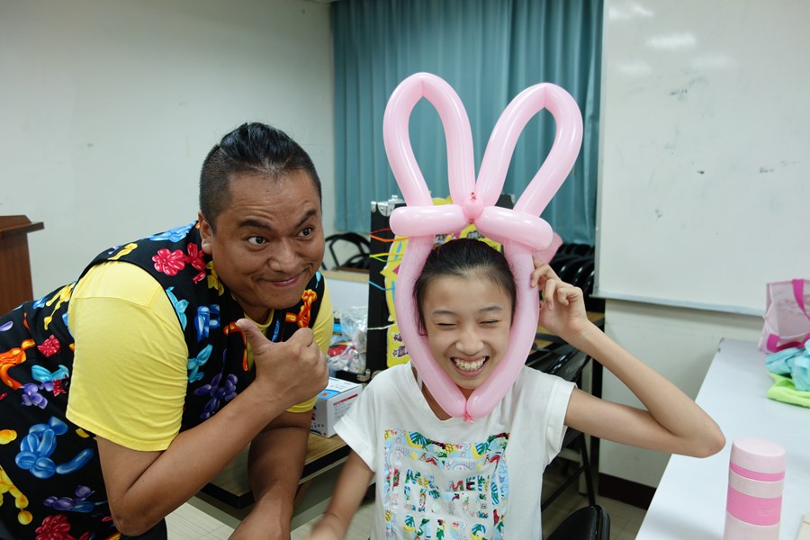 107年新住民親子生活適應輔導班第3天活動照片-學生戴著兔子耳朵造型氣球開心與老師合照