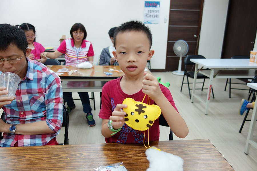 107年新住民親子生活適應輔導班第3天活動照片-小弟弟開心拿著自己製作的老虎香包